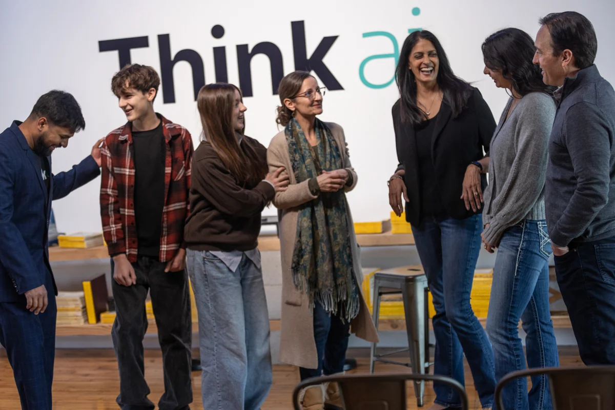 A group gathered together, talking and smiling, in the ThinkAI learning space.