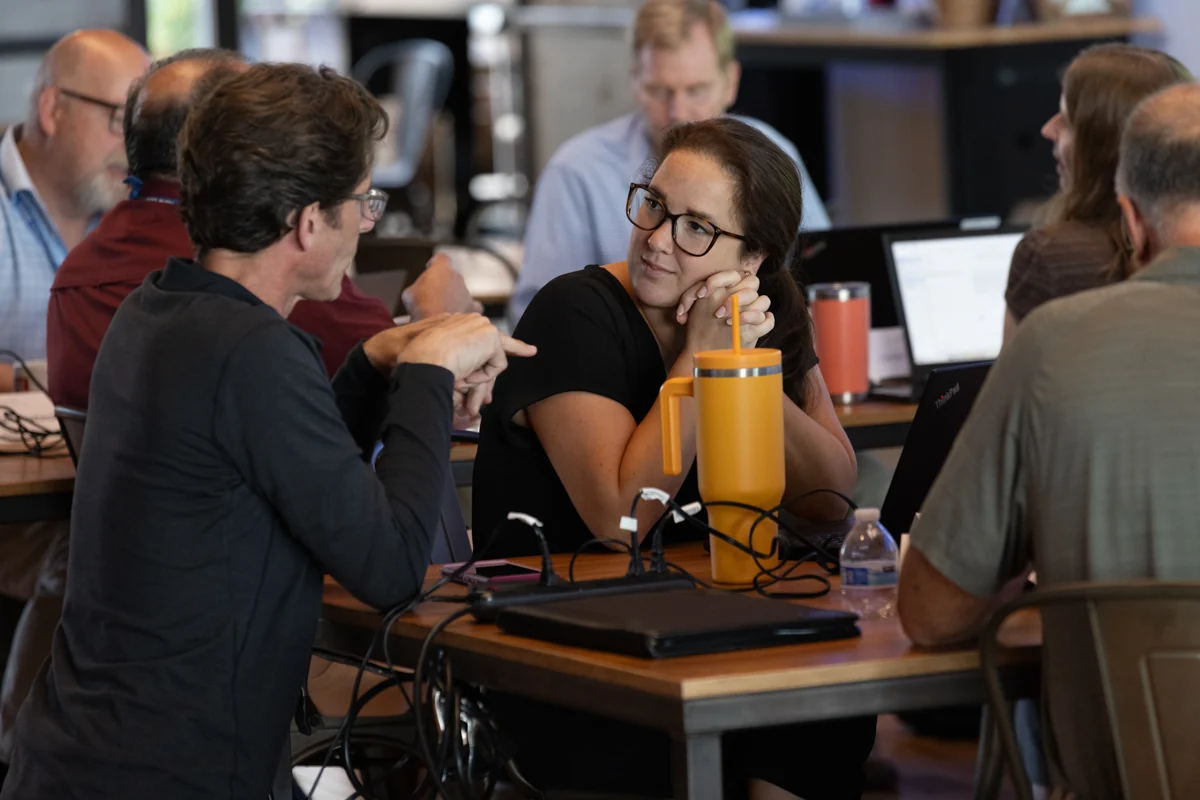 Two people in conversation at a table during a workshop.