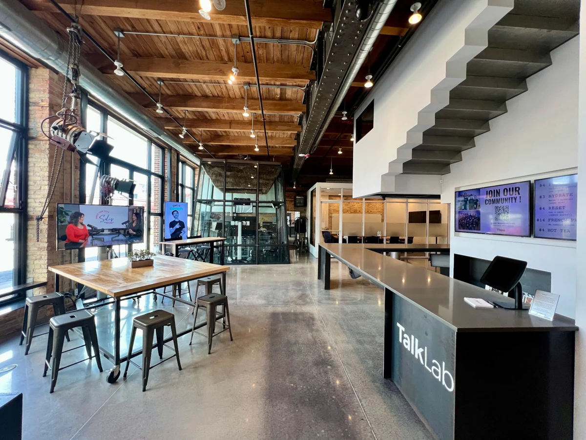 The TalkLab lobby with a large shared table, studio, and reception counter.