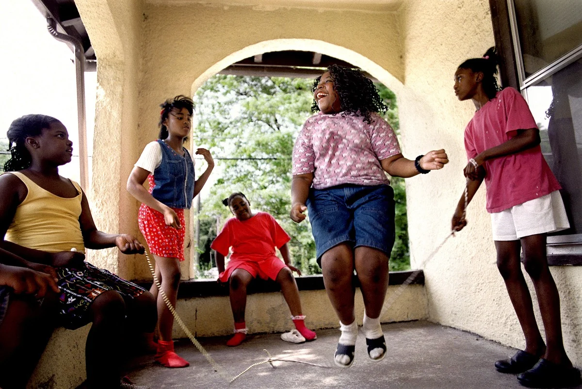 Children playing jump rope together on a porch.