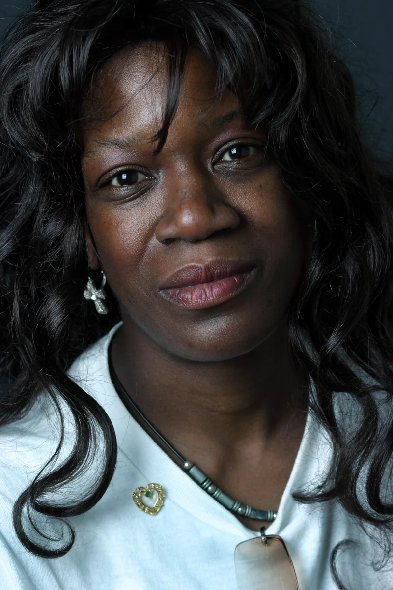 A close-up photographic portrait of a woman looking toward the camera.