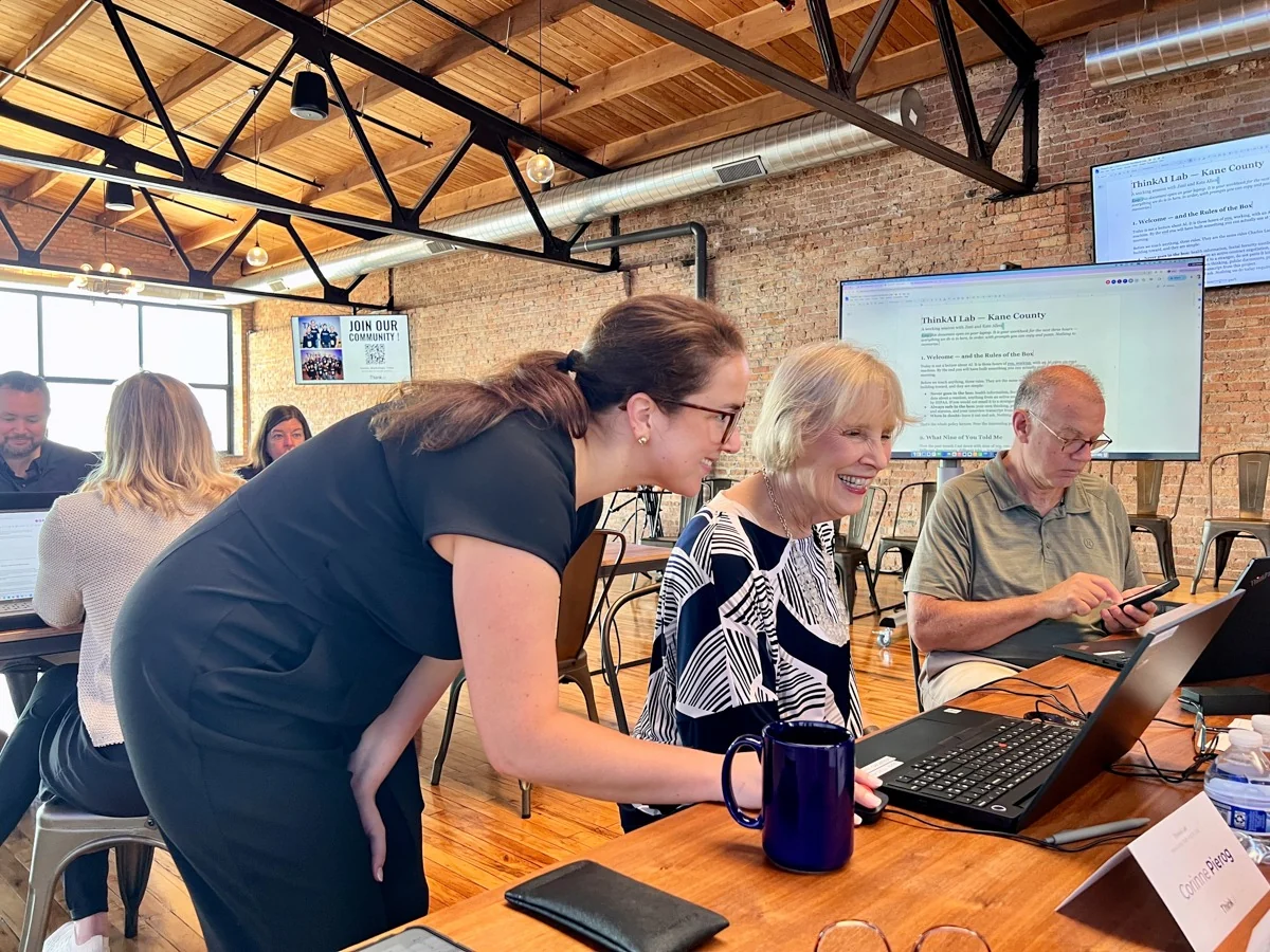 People working together at laptops in a sunlit workshop.